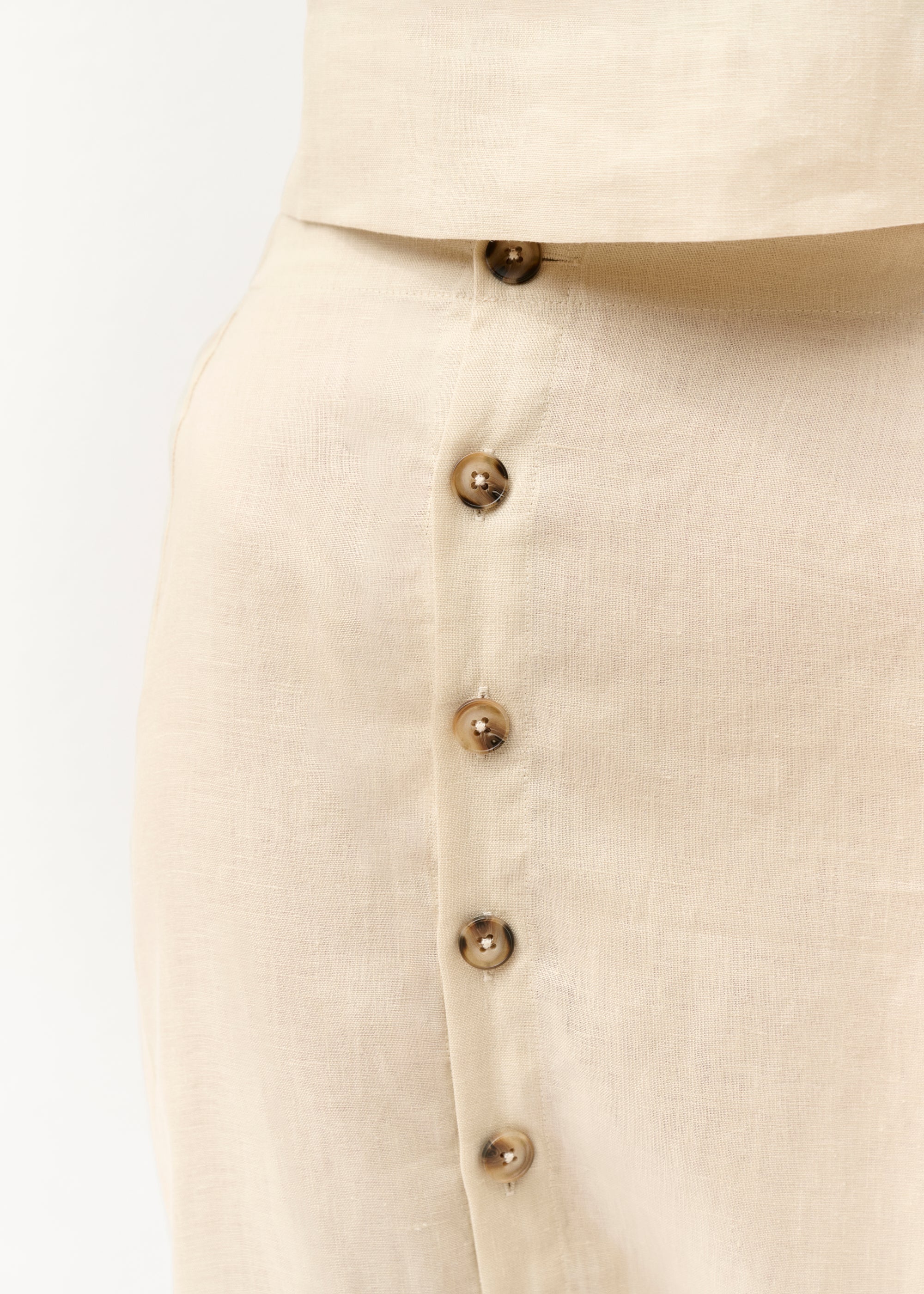 Detailaufnahme der Knopfleiste des Rocks. Die Struktur des Leinenstoffs ist gut sichtbar.