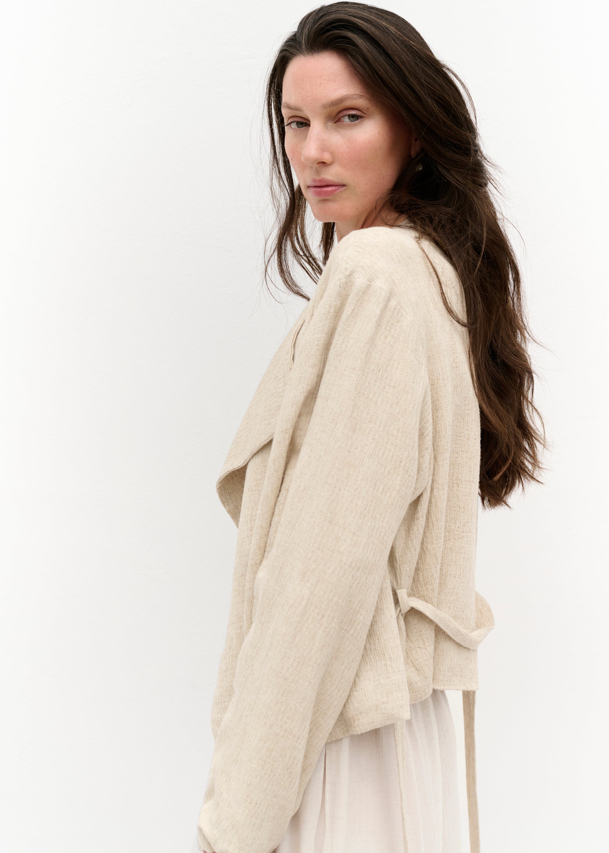 Seitliche Nahaufnahme der Wickeljacke mit Fokus auf die Struktur des Stoffes und den schlichten Schnitt.