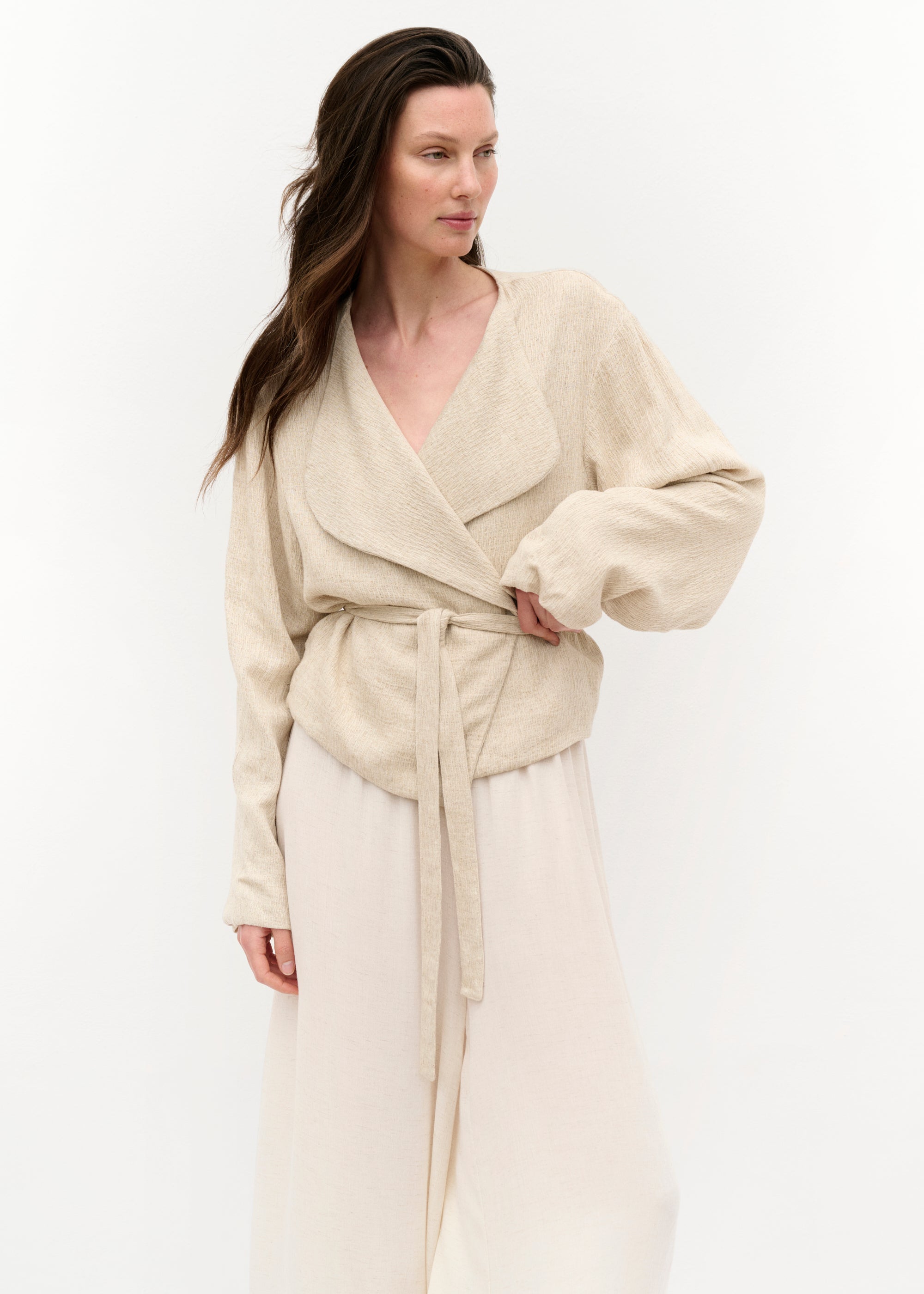 Frontansicht mit geschlossener Jacke, der Gürtel ist gebunden und betont die Taille; darunter trägt das Model keine sichtbare Bluse.