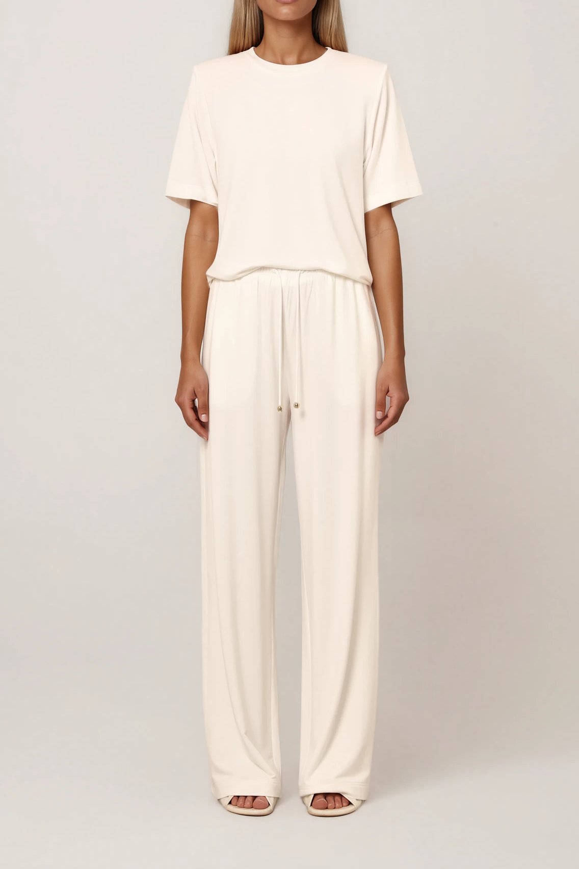 Cremefarbenes T-Shirt mit Rundhalsausschnitt und kurzen Ärmeln, locker geschnitten, kombiniert mit weiter Hose, Seitenansicht