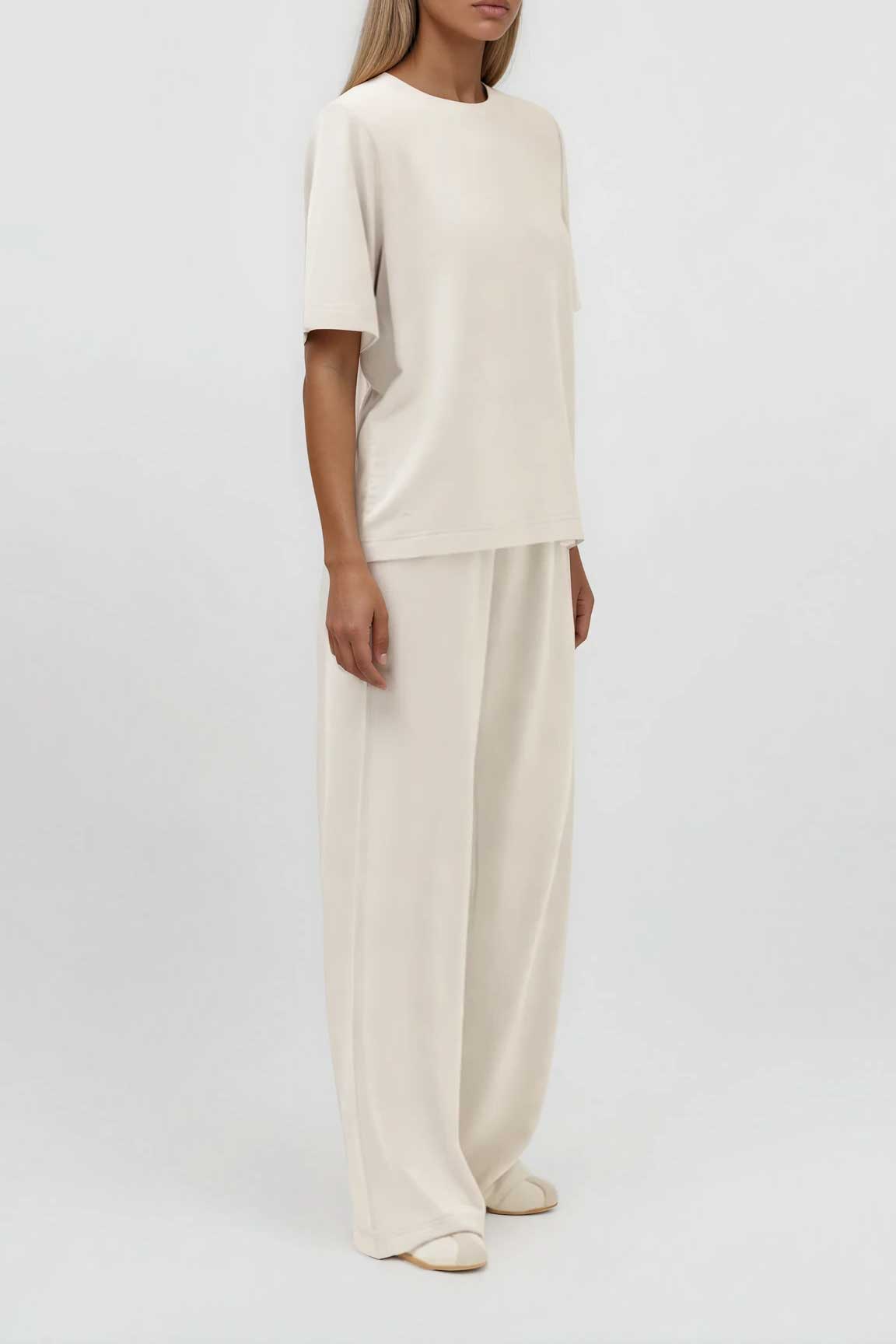 Cremefarbenes T-Shirt mit Rundhalsausschnitt und kurzen Ärmeln, locker geschnitten, kombiniert mit weiter Hose, Seitenansicht