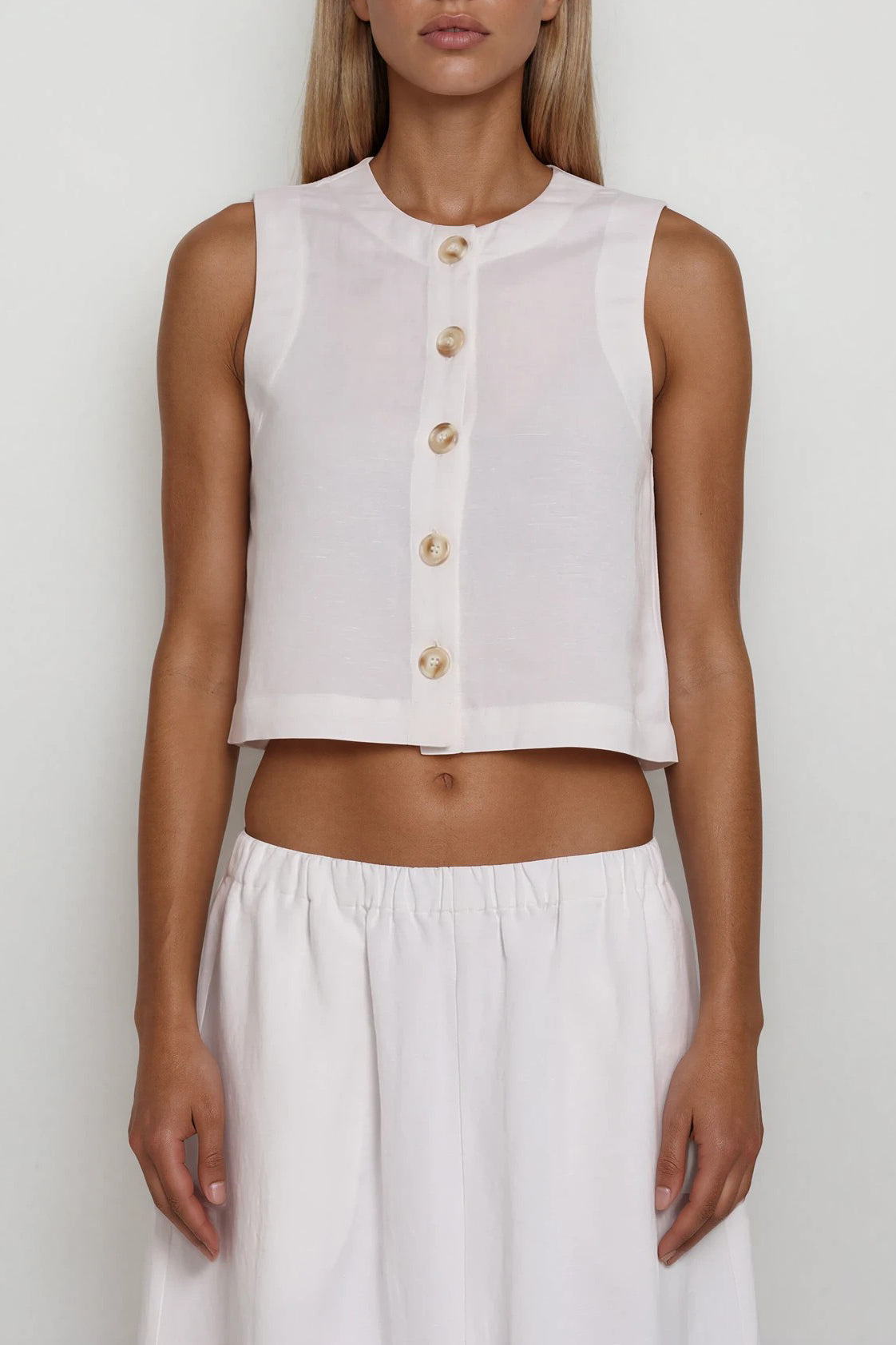 Ärmelloses weißes Crop-Top mit Rundhalsausschnitt und Knopfleiste, kombiniert mit langem Rock
