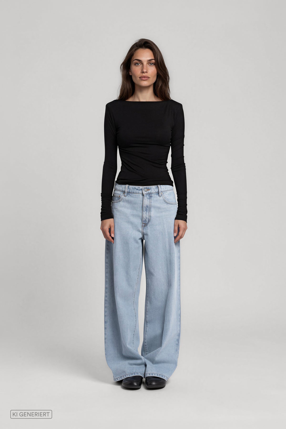 Frontalansicht eines Models in einem schwarzen, figurbetonten Langarmshirt mit weitem Rundhalsausschnitt, kombiniert mit einer hellblauen, weit geschnittenen Jeans.