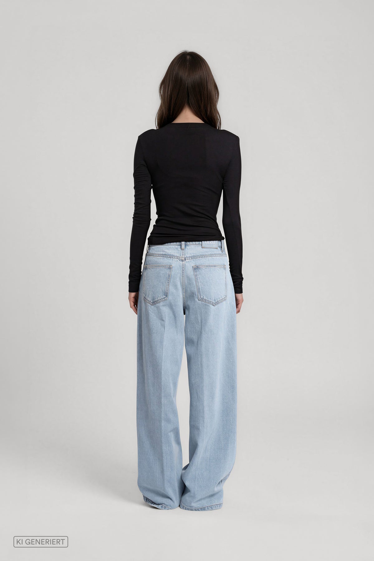 Rückansicht eines Models in einem schwarzen, langärmligen Oberteil und einer hellblauen, weit geschnittenen Jeans mit Gesäßtaschen.