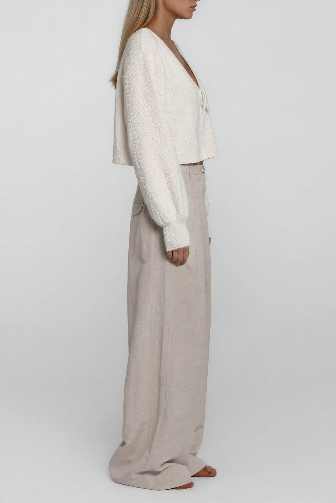 Seitliche Ansicht eines cropped Strick-Cardigans in Offwhite mit voluminösen Ärmeln