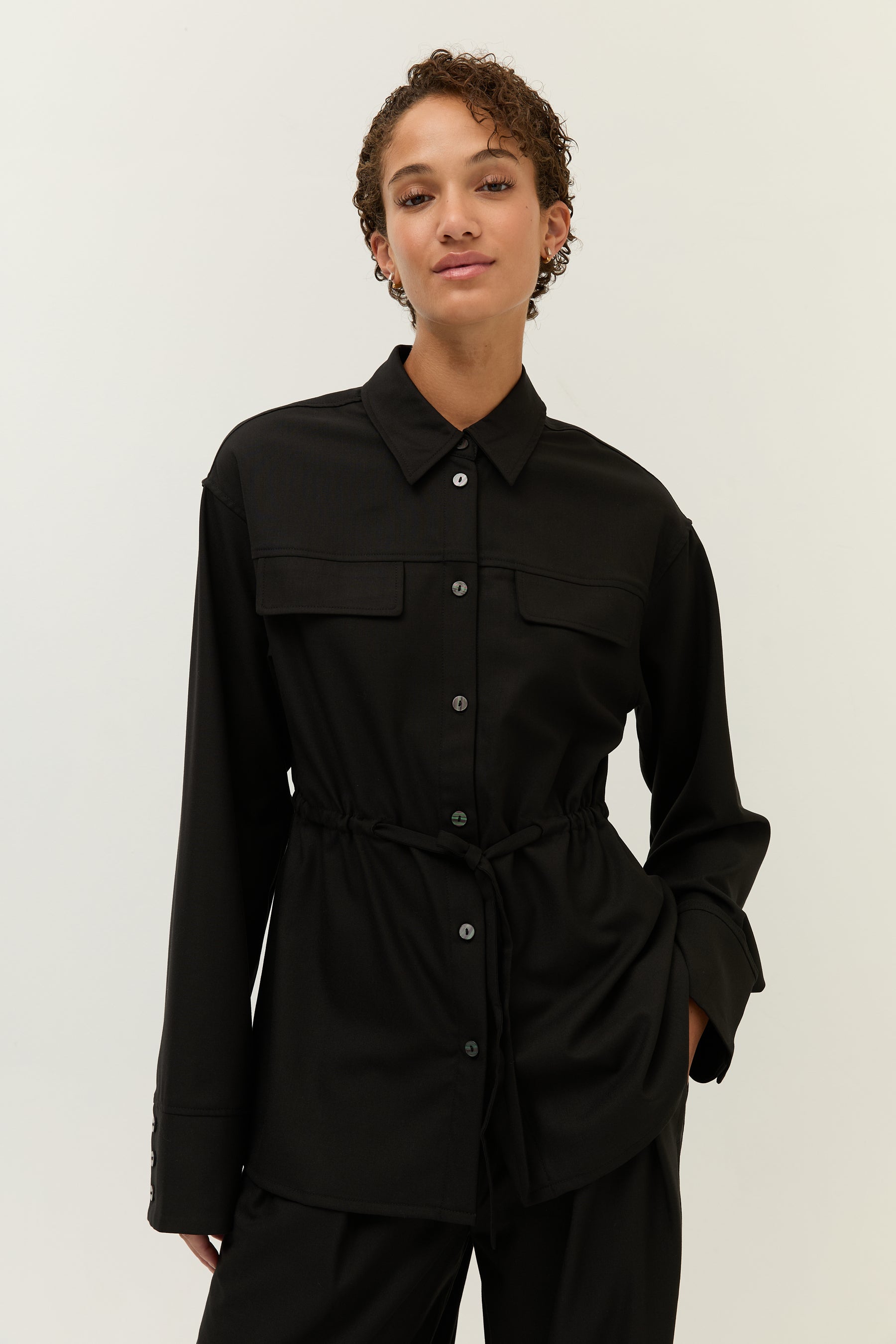 Frontalansicht mit gebundenem Taillenzug, der dem Hemd eine feminine Silhouette verleiht.