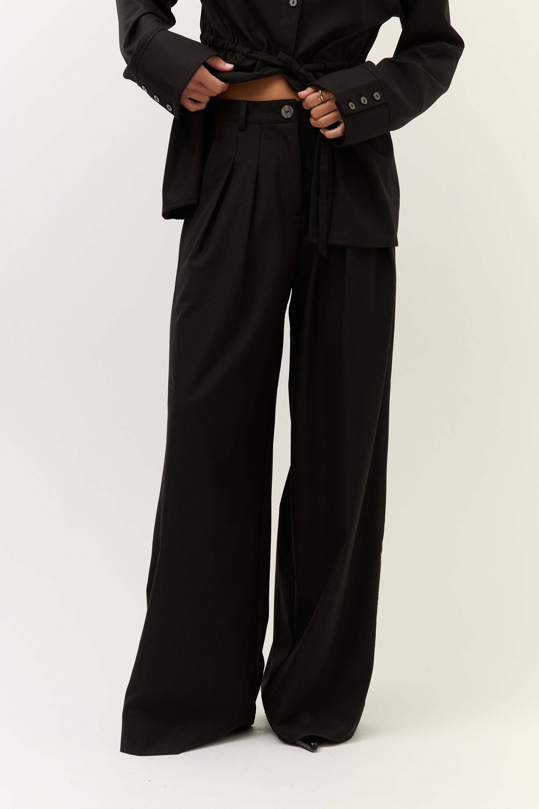 Frontalansicht, leicht geöffnet
Zweiteiler in Schwarz mit offenem Hemd und sichtbarem Hosenbund, Fokus auf lässigen Look.