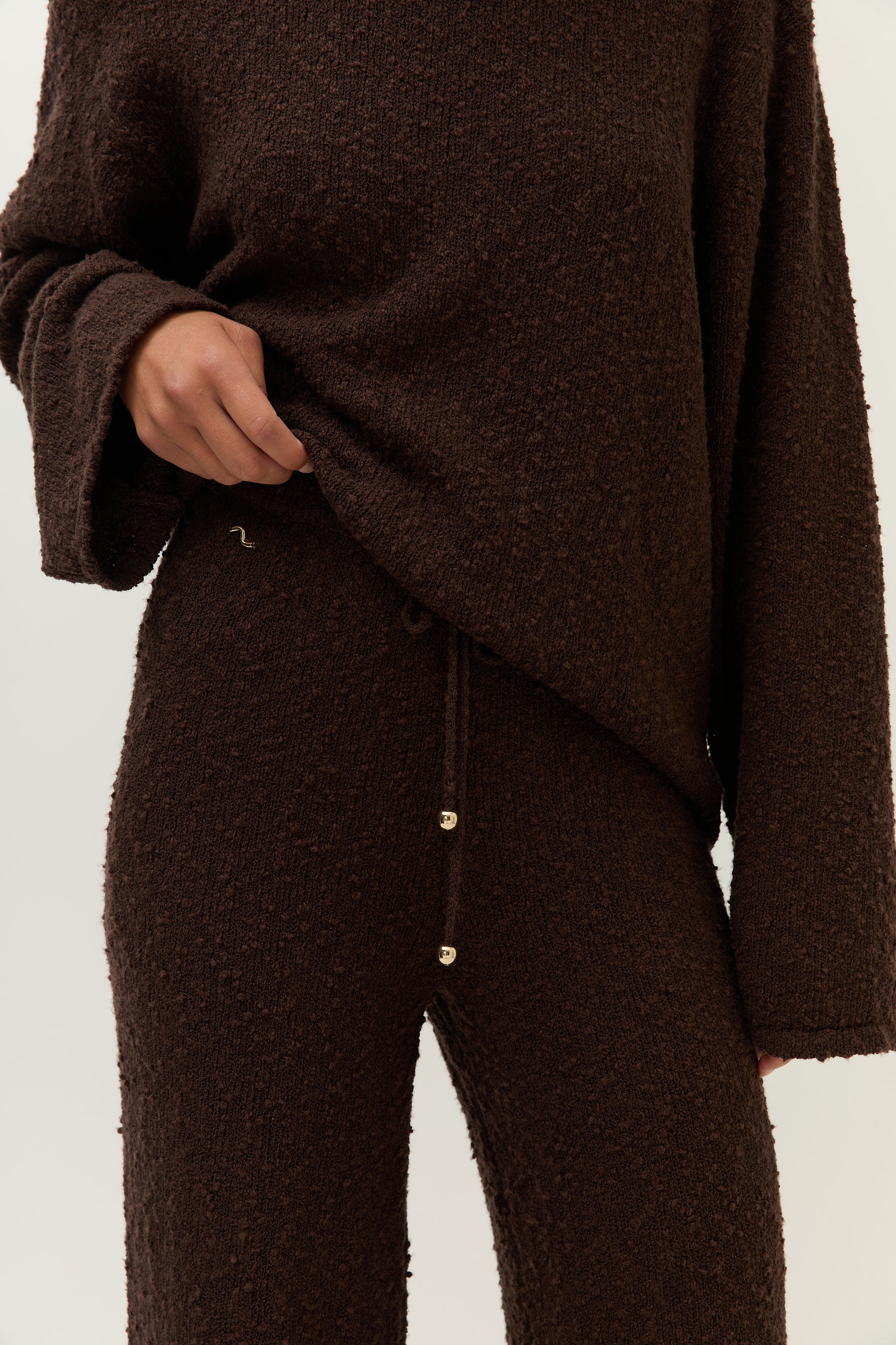 Nahaufnahme vorn: Detail des elastischen Bunds mit Kordelzug, teils verdeckt vom locker fallenden Pullover.