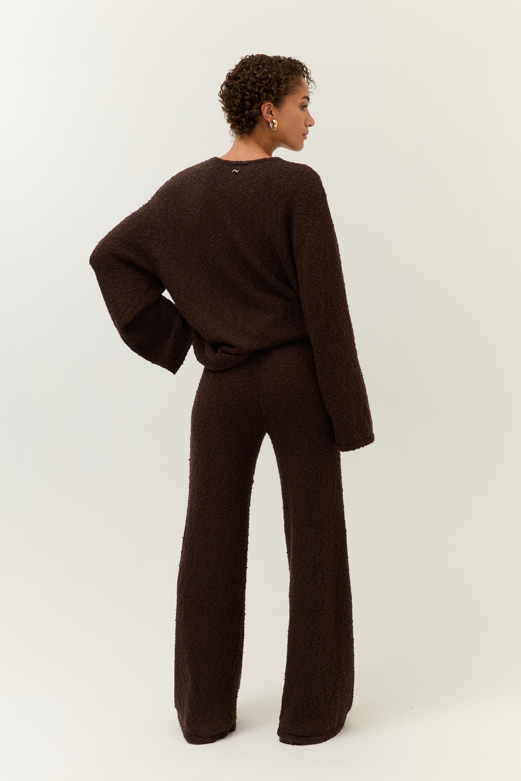 Rückenansicht: Rückansicht des Sets, der Pullover fällt locker über die Hose, sichtbares Logo im Nacken.