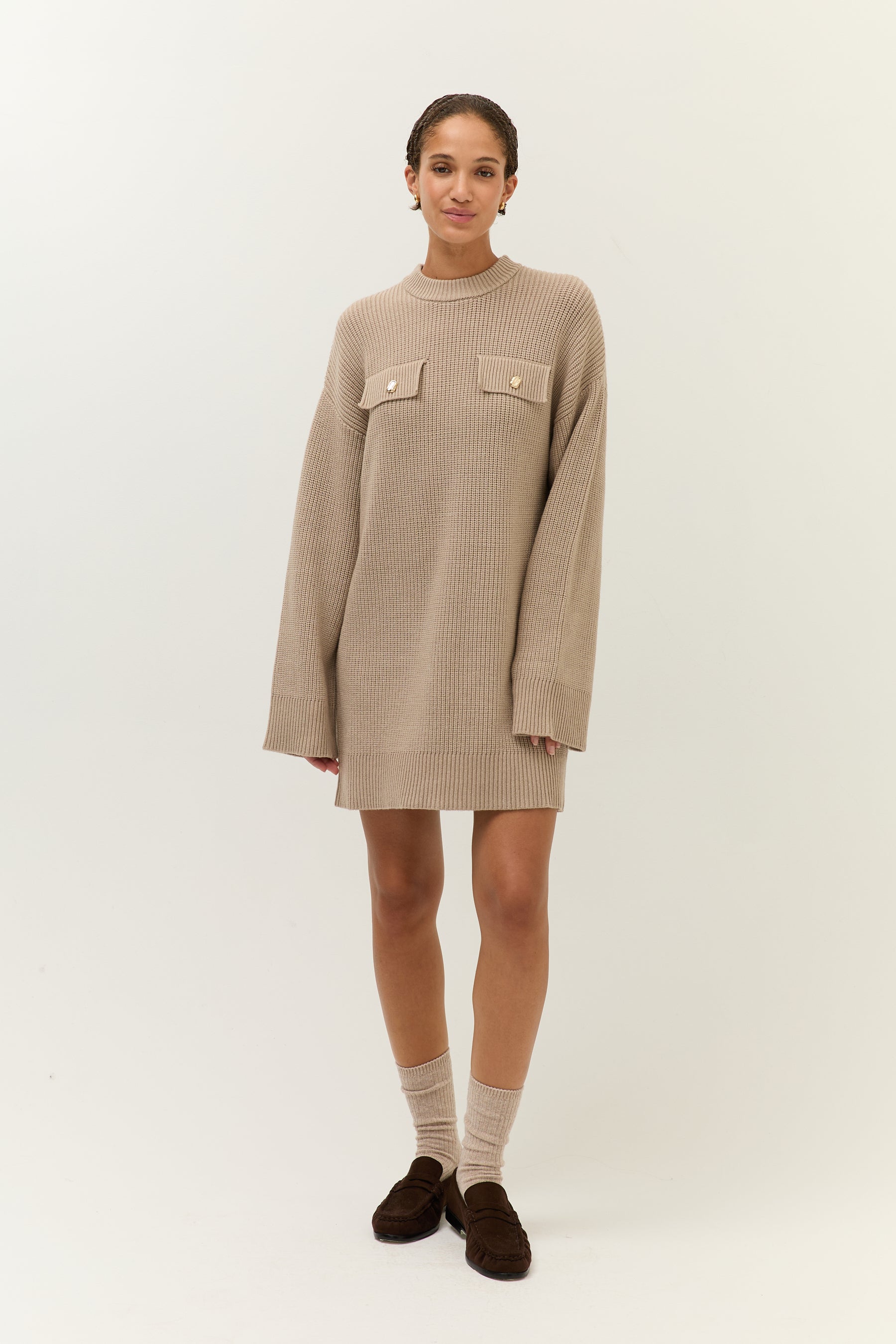 Frontalansicht, Ganzkörper
Model trägt ein beiges Strickkleid mit langen Ärmeln und aufgesetzten Brusttaschen mit goldenen Knöpfen.