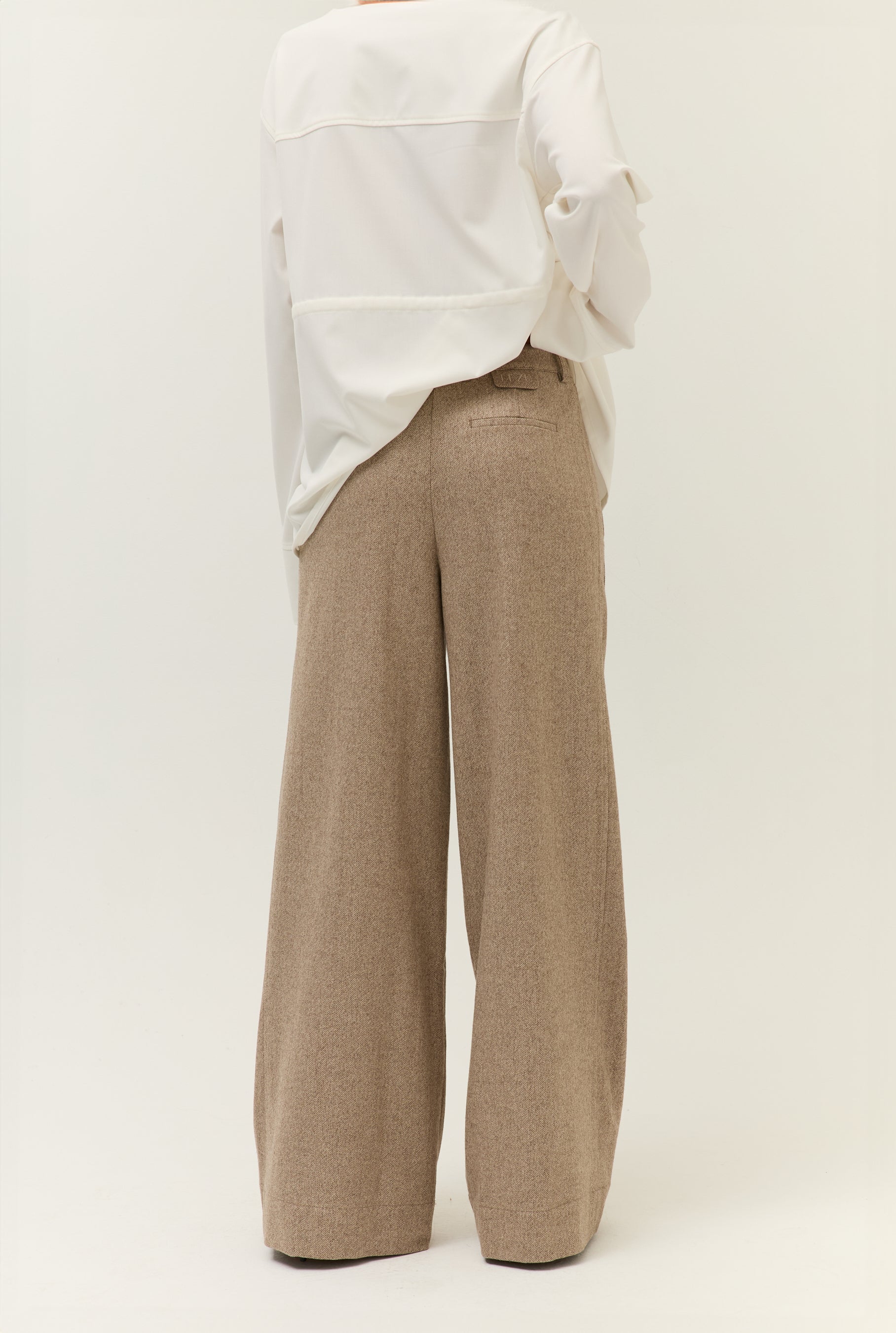 Rückansicht der Hose mit Hemd
Rückansicht des weißen Hemds über einer hellbraunen, weit geschnittenen Hose. Klare Linien und reduziertes Styling.