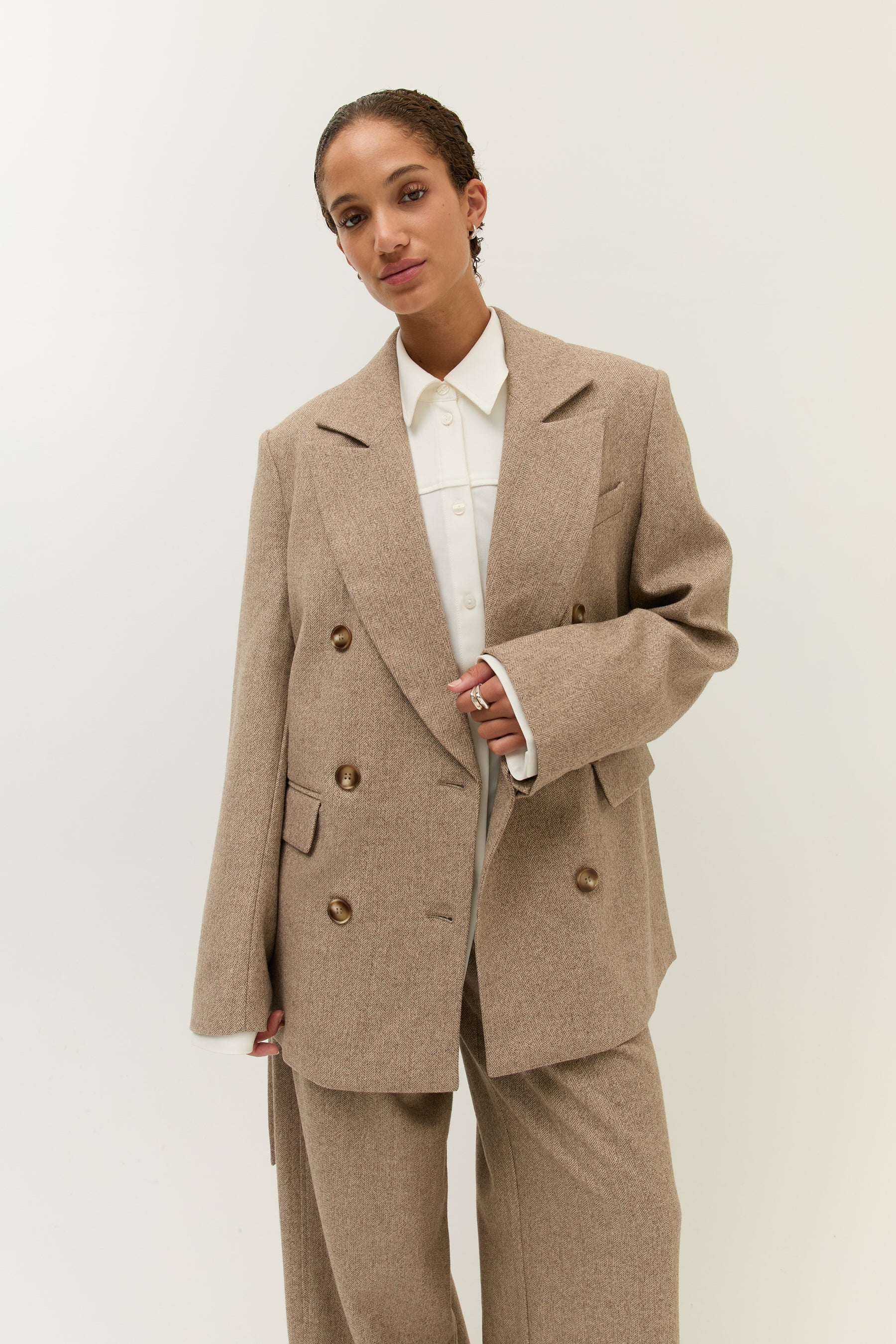 Halbnahe Aufnahme des Models mit geöffnetem Blazer, unter dem ein weißes Hemd mit klassischem Kragen zu sehen ist.