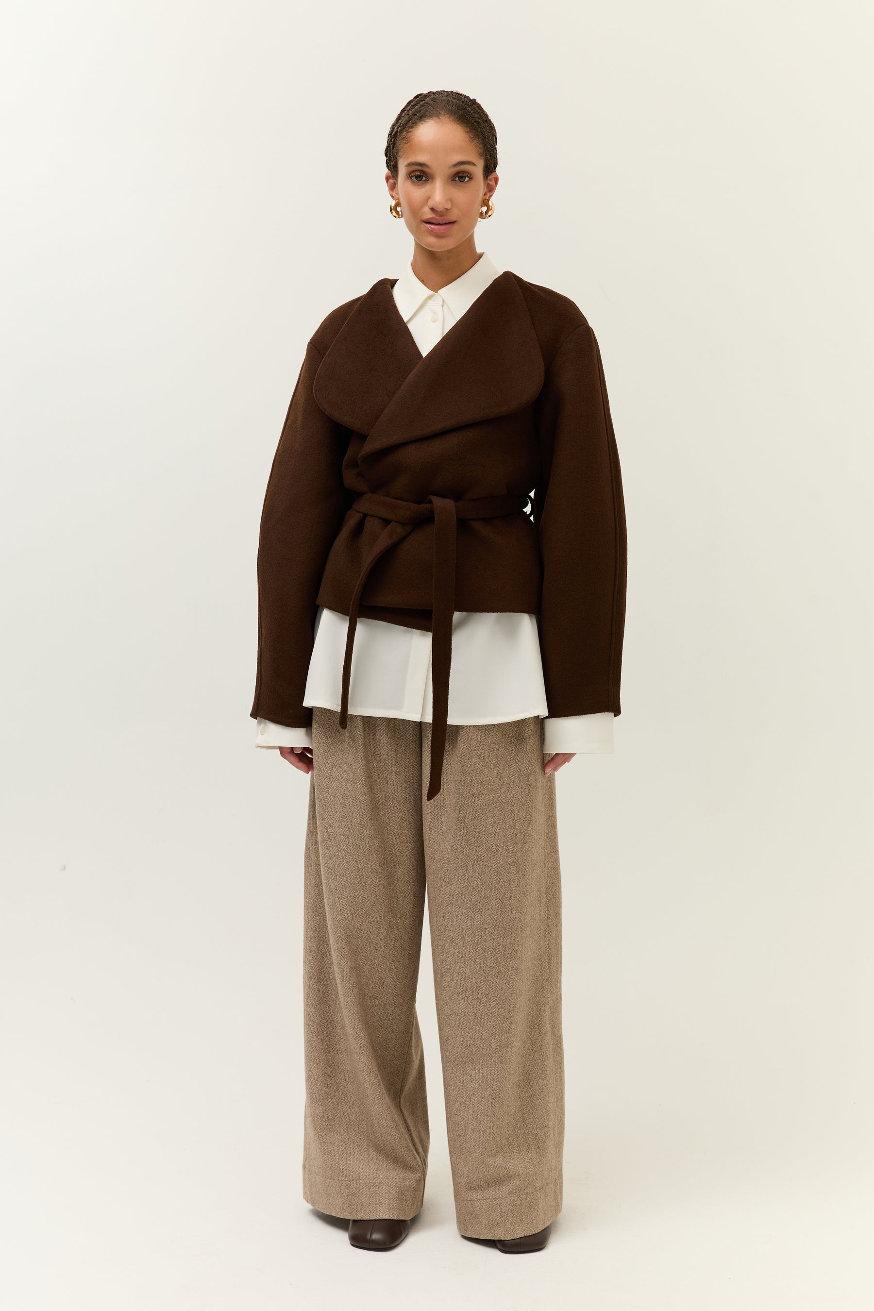 Vollansicht frontal, mit Gürtel geschlossen: Die Jacke ist nun mit dem Stoffgürtel auf Taille gebunden, der Lagenlook mit Hemdbluse und Hose bleibt erhalten.