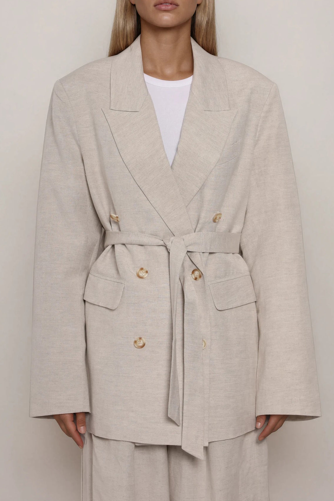 Beiger doppelreihiger Blazer mit Taillengürtel und Reverskragen, Knopfleiste, leicht taillierte Silhouette, Frontansicht