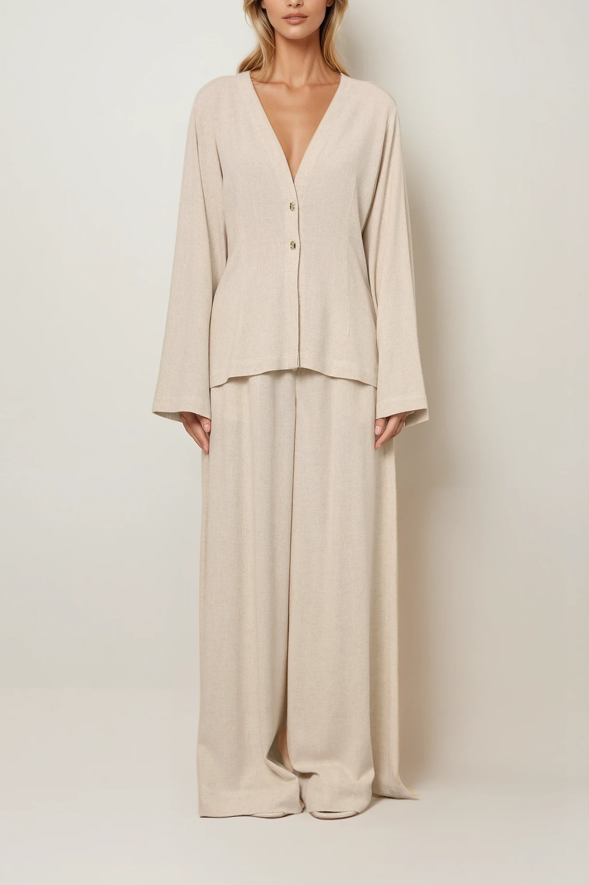 Beige Bluse mit V-Ausschnitt und Knopfleiste, locker geschnitten mit langen Ärmeln, kombiniert mit weiter, fließender Hose im monochromen Look.