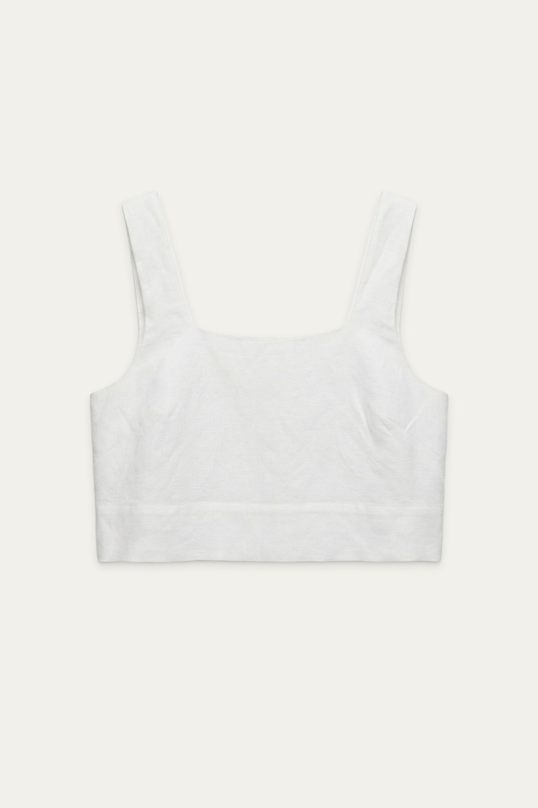 Weißes Crop-Top mit breiten Trägern und geradem Ausschnitt, flach liegend vor neutralem Hintergrund
