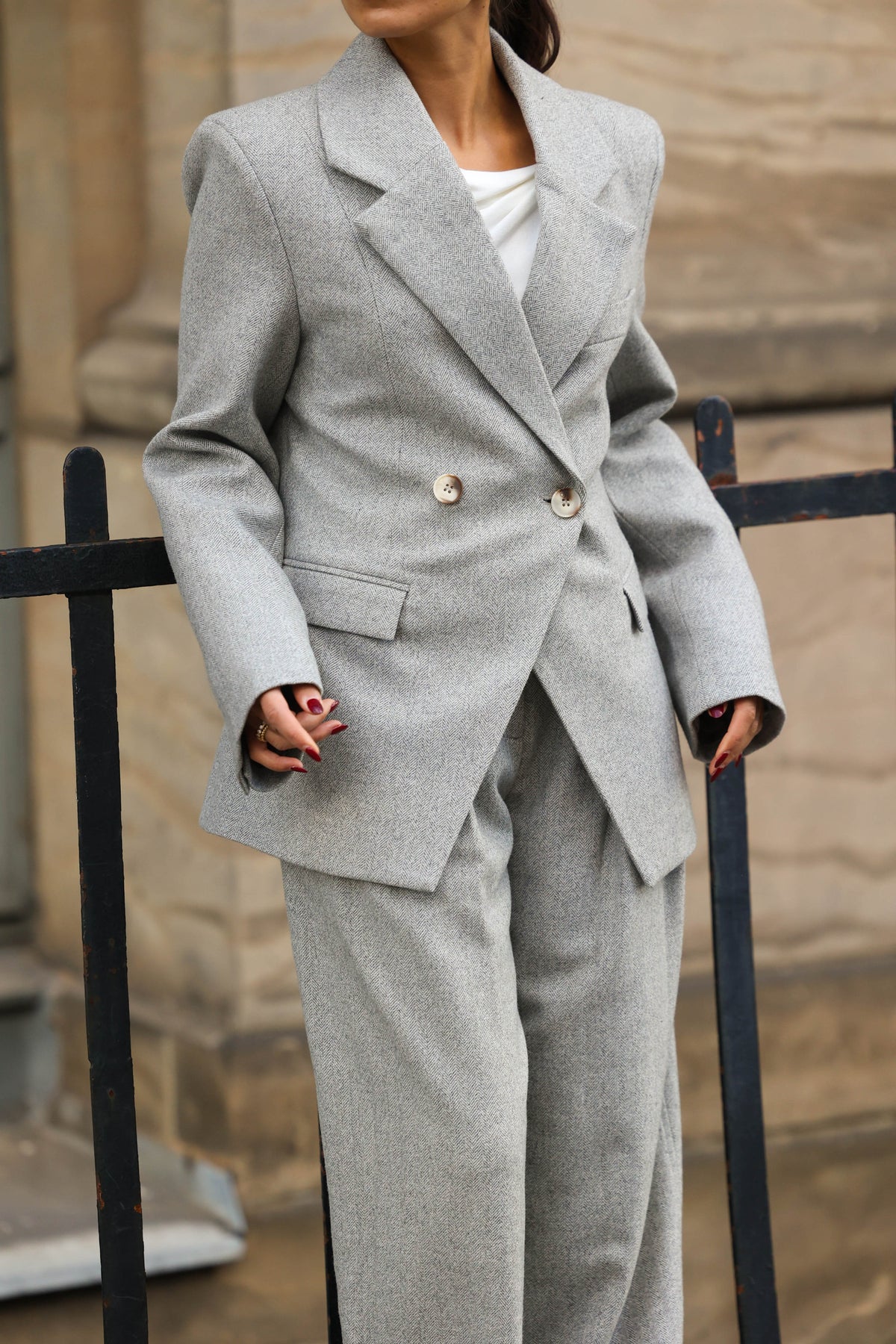 DELIA Blazer Herringbone Grey – zweireihiger Blazer in grauem Fischgrat-Muster mit Reverskragen und Hornknöpfen, getragen mit passender weiter Hose und weißem Top