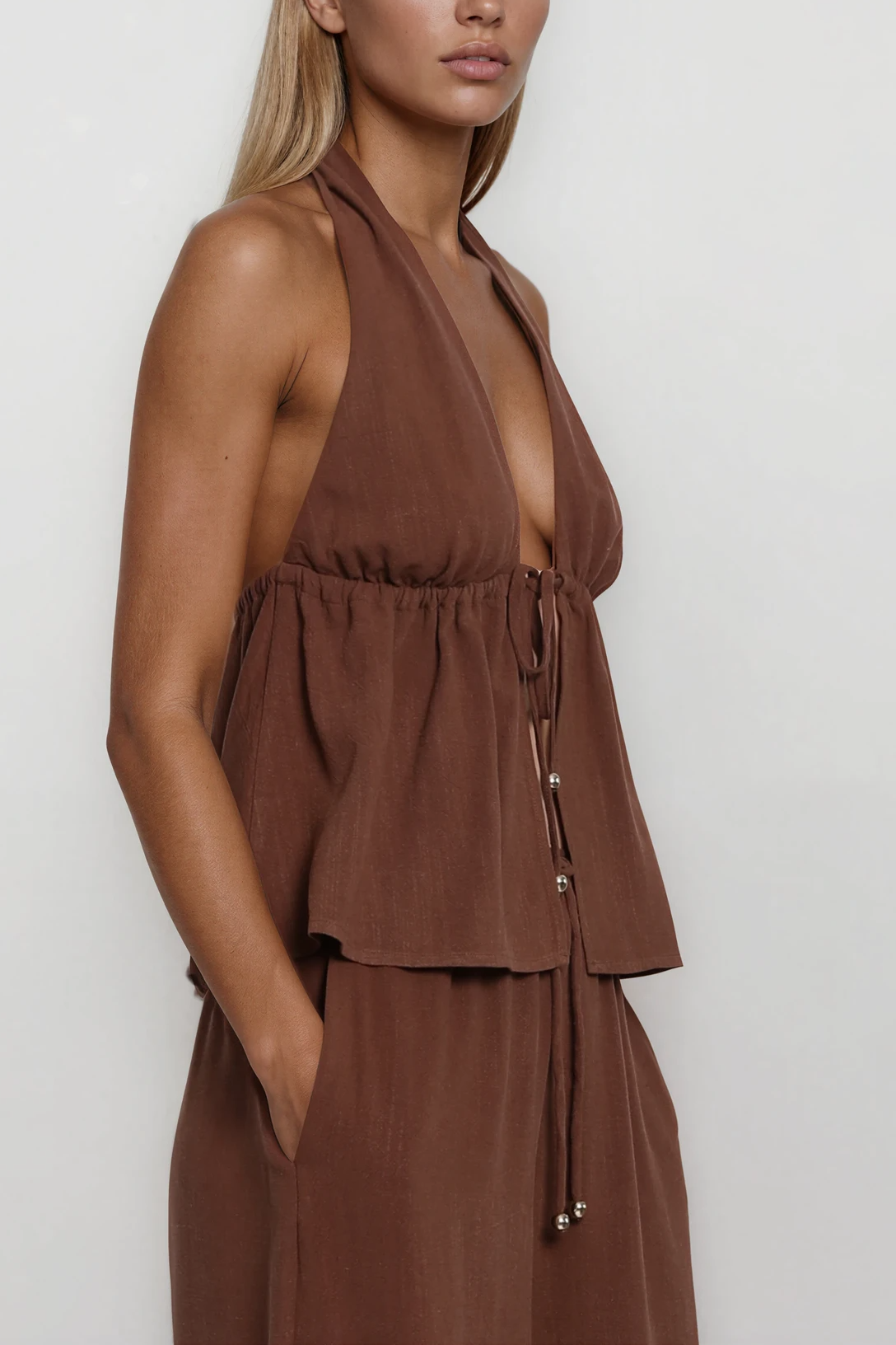 Detailaufnahme des braunen Neckholder-Tops mit Bindeband und geraffter Taille