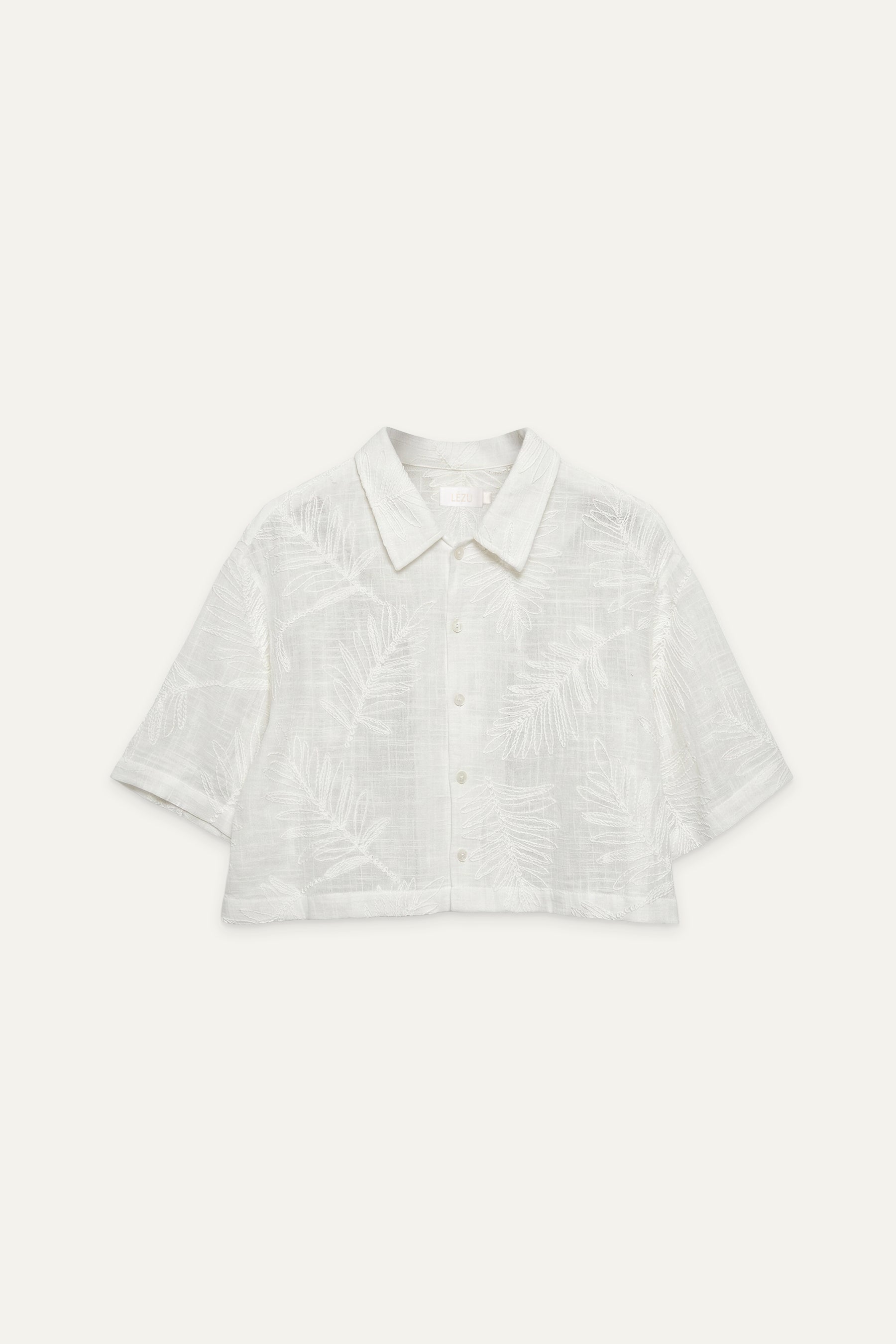 Kurz geschnittene Bluse in Off-White mit Kragen, Knopfleiste und eingewebtem Blattmuster, flach liegend