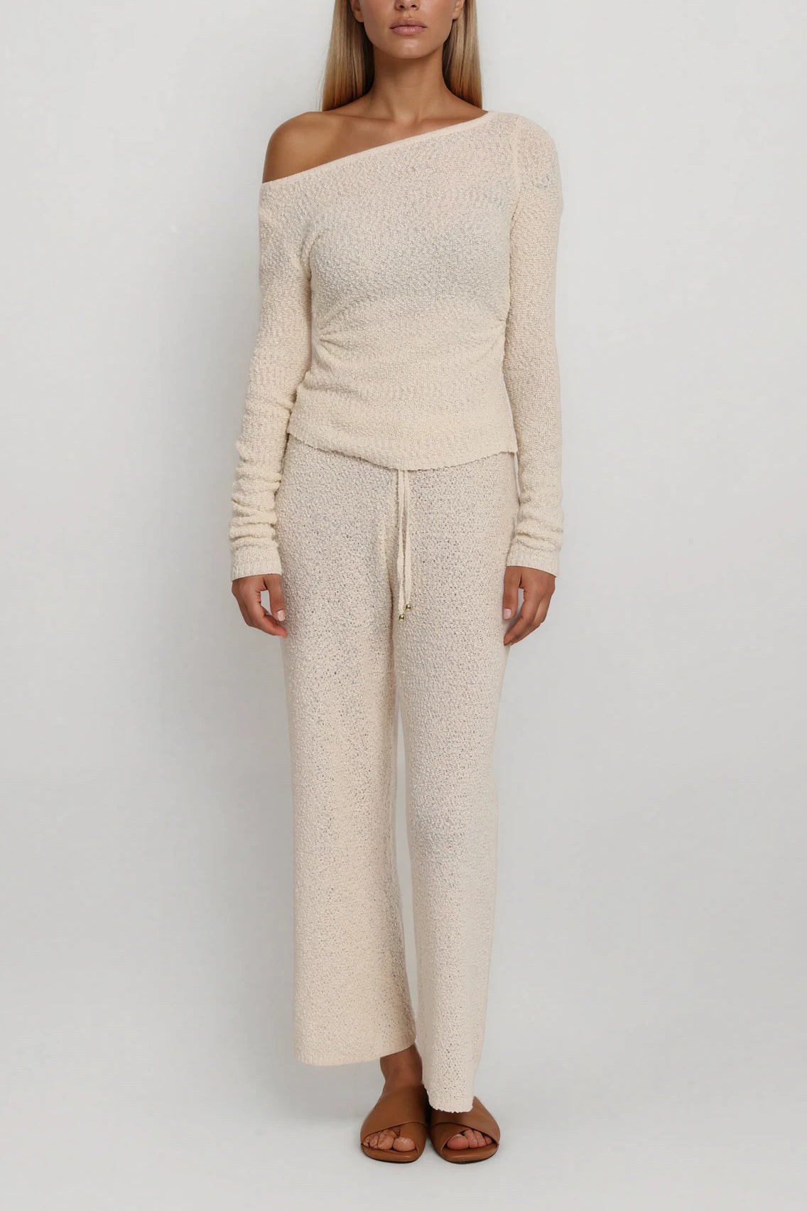 Frontansicht eines beigen Strick-Sets mit asymmetrisch getragenem One-Shoulder-Oberteil und weiter Hose