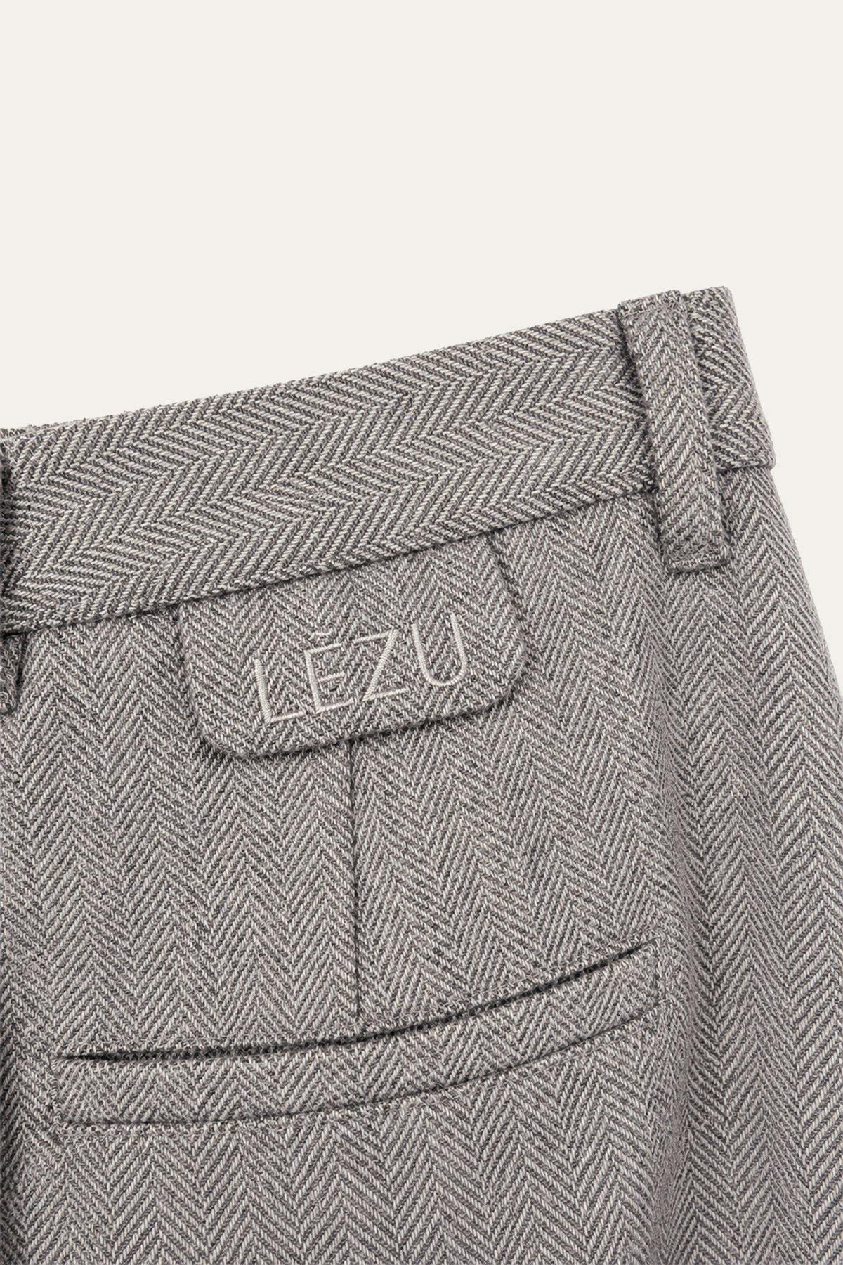 Detailaufnahme der grauen Ada Pants mit Fischgratmuster von hinten: Bund mit Gürtelschlaufen, Pattentasche mit LEZU-Schriftzug und darunter eine Paspeltasche