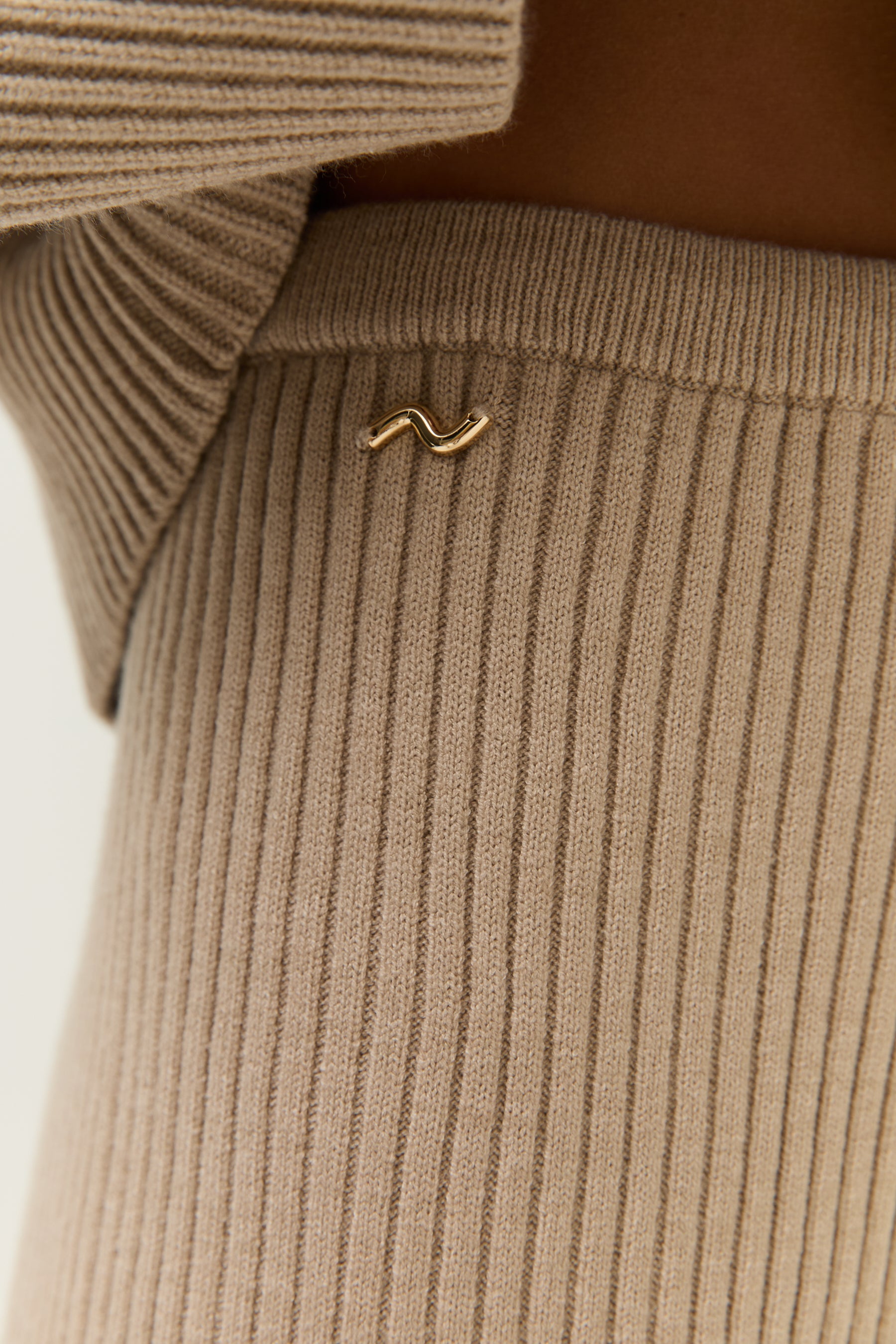 Extreme Nahaufnahme des gerippten Strickmaterials in Beige – Fokus auf Textur und Struktur des Stoffes.