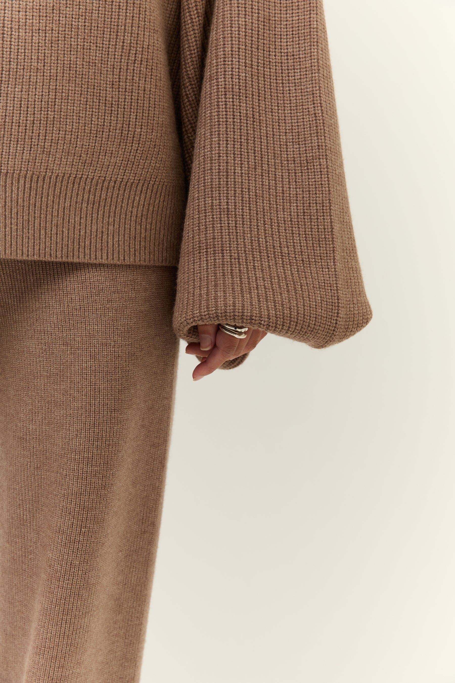 Bild 3: Nahaufnahme der weiten Strickärmel des Pullovers, die locker über die Hand fallen. Die Textur des Materials ist deutlich sichtbar.