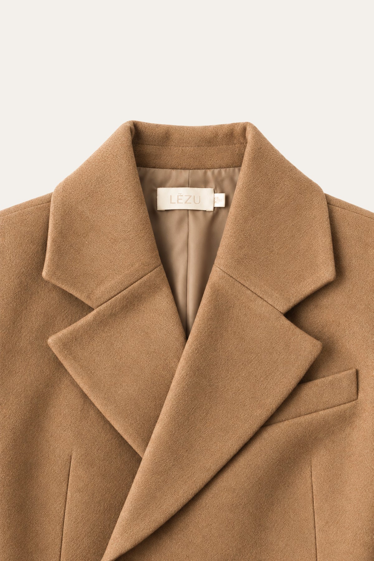 Detailansicht eines camelbraunen Blazers mit breitem Reverskragen, Brusttasche und sichtbarem LEZU-Etikett am Kragen.