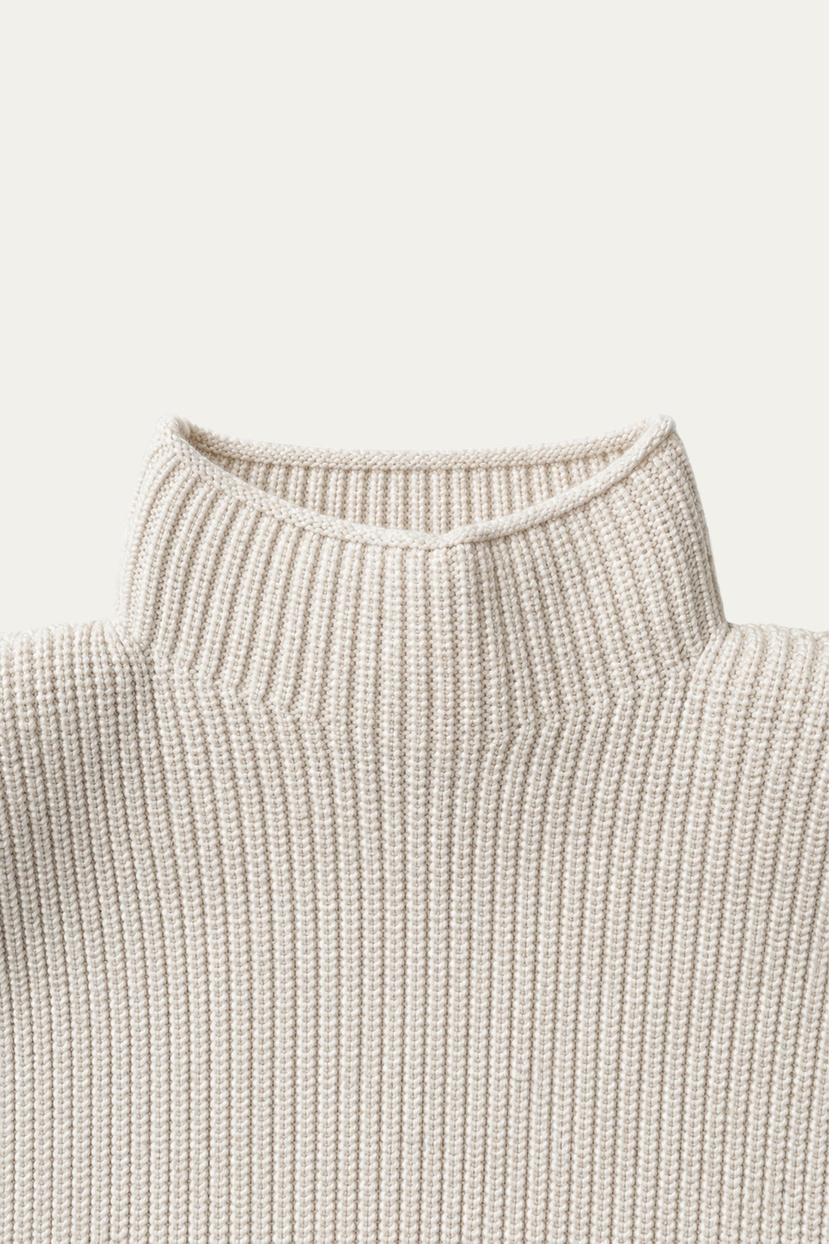 Detailaufnahme eines cremefarbenen Strickpullovers mit markanter Rippenstruktur und hohem Stehkragen.