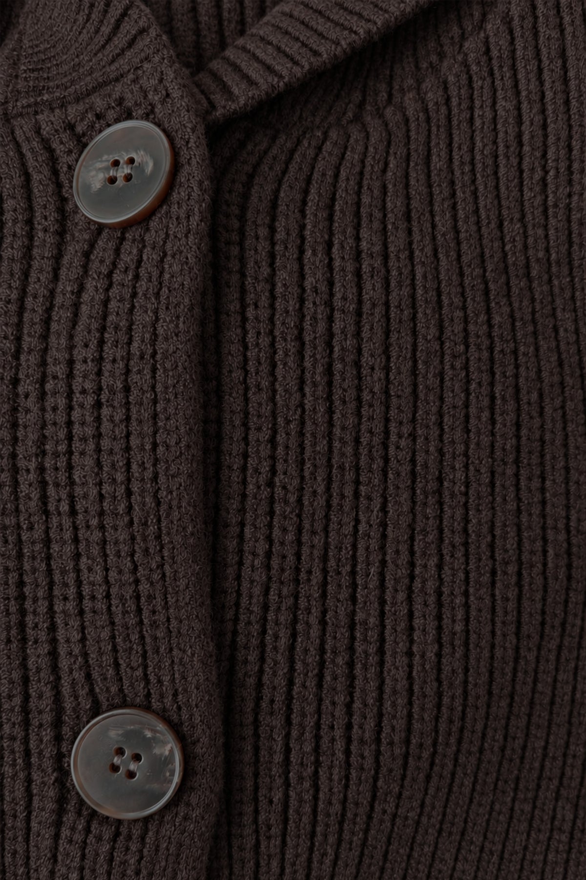 Detailaufnahme eines dunkelbraunen Strickoberteils mit ausgeprägter Rippenstruktur und zwei braunen Knöpfen.