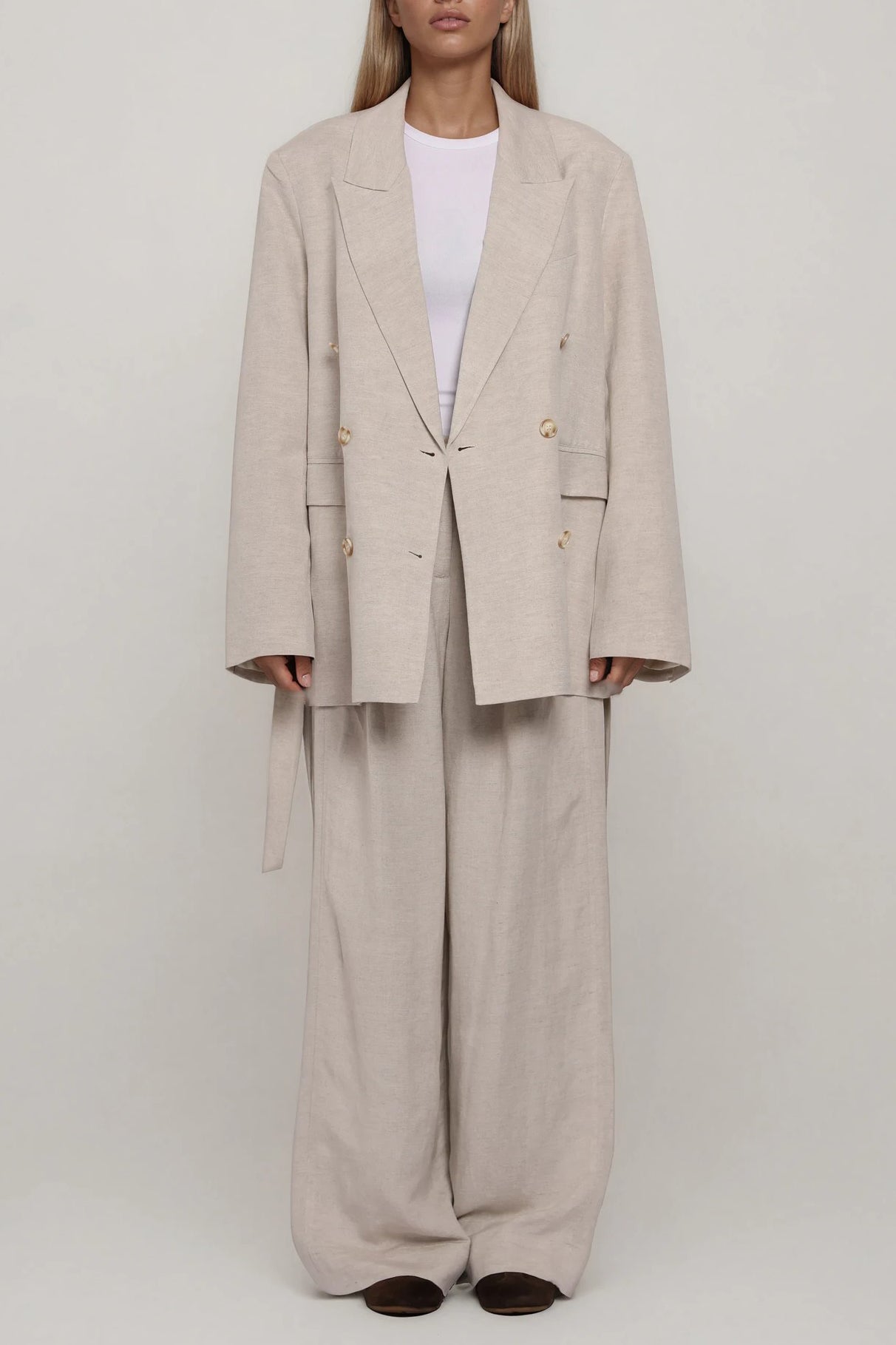 Beiger doppelreihiger Blazer mit Reverskragen und Knopfleiste, gerade Passform, kombiniert mit weiter Hose, Ganzkörperansicht