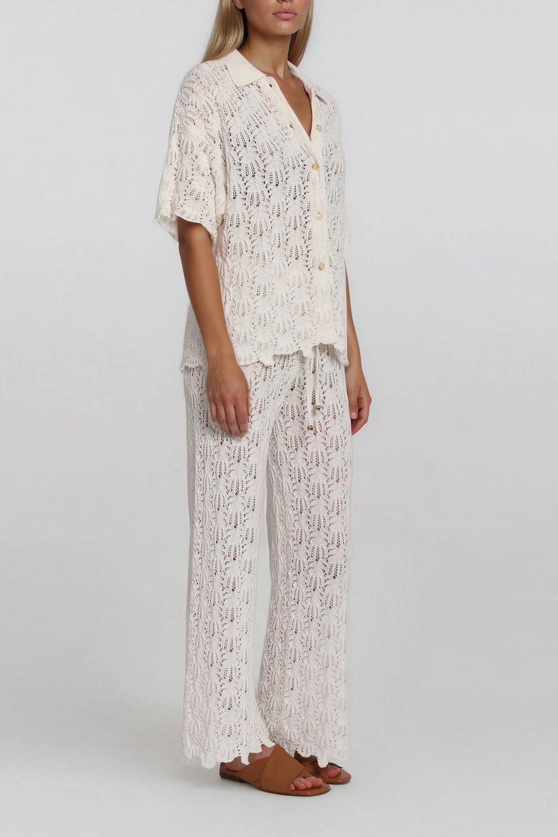 Schrägansicht eines weißen Strick-Sets mit kurzärmligem Cardigan und weiter Hose aus Lochstrick