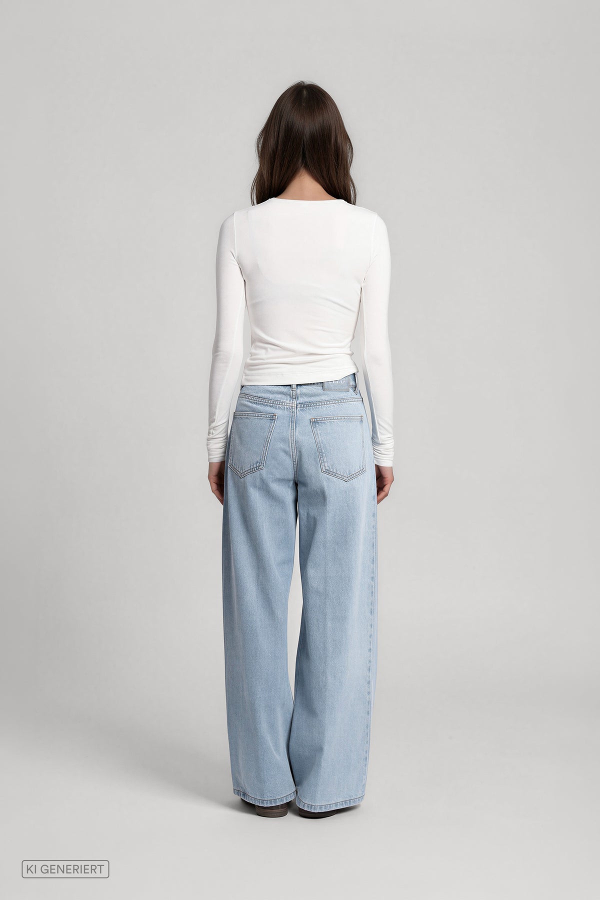 Rückansicht eines Models in einem weißen, langärmeligen Oberteil und einer hellblauen, weit geschnittenen Jeans mit Gesäßtaschen.