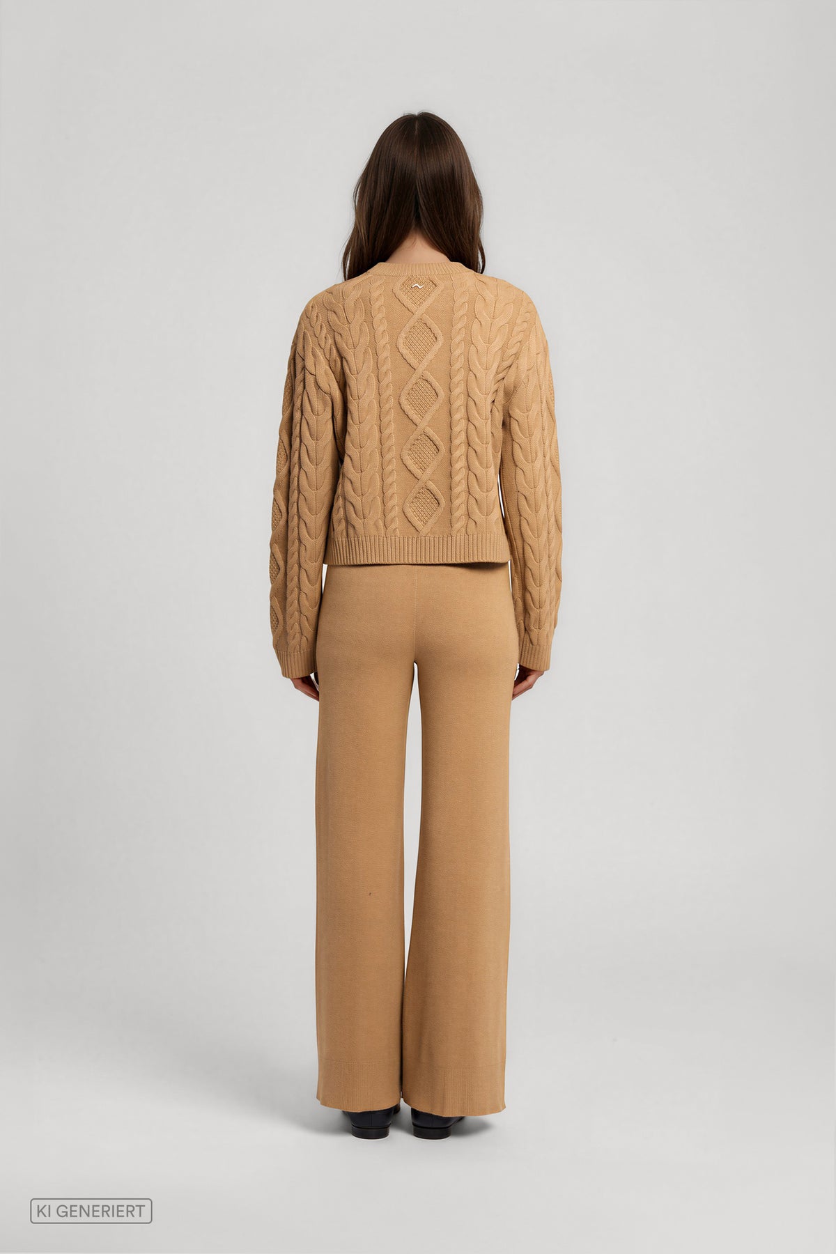 Rückansicht eines Models in einem camelbraunen Strickset aus Pullover mit Zopfmuster und weit geschnittener Strickhose.